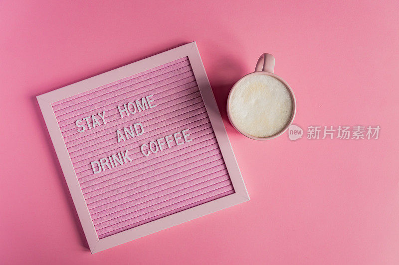 Top view of Pink Coffee cup with cappuccino and quote呆在家里喝咖啡。自我隔离和隔离运动，以保护自己不受流行病的影响